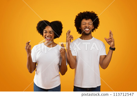 Superstitious african american couple cross fingers on yellow Superstitious african american couple cross fingers on yellow 113712547