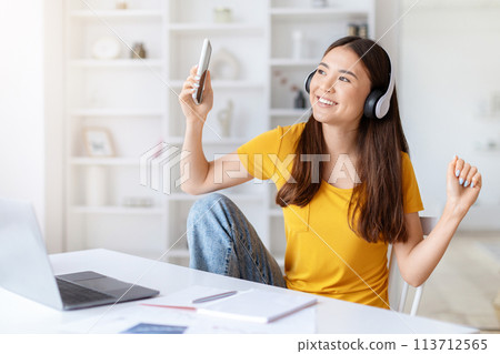 Woman enjoying music and dancing at desk 113712565