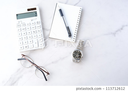 Image of a person managing household finances with a calculator, pen, and notepad 113712612