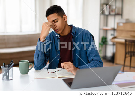 Focused man working on laptop at home desk 113712649