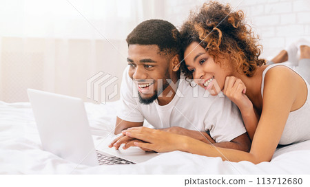 Couple enjoying content on a laptop in bed Couple enjoying content on a laptop in bed 113712680