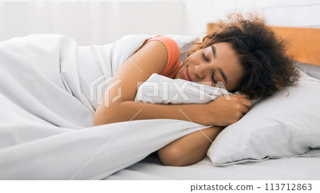 African-american woman sleeping and hugging white blanket 113712863