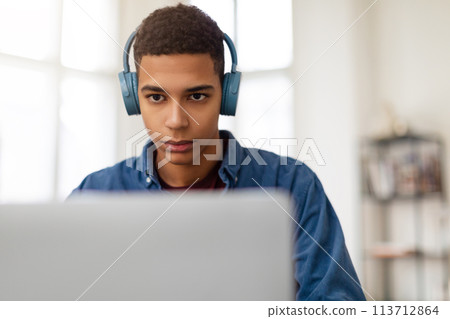 Young man with headphones using laptop 113712864