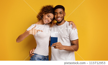 Happy couple showing passports and pointing on yellow background 113712953