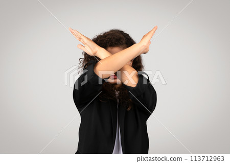 Curly haired woman with arms crossed over face 113712963