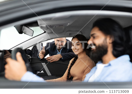 Salesperson giving a thumbs up to car buyers Salesperson giving a thumbs up to car buyers 113713009