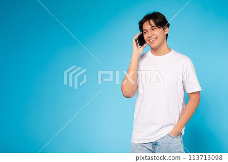 Young guy talking on the phone happily Young guy talking on the phone happily 113713098