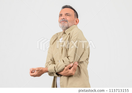 Senior man rubbing his elbow against studio background 113713155