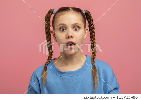 Young girl with shocked expression on pink background 113713486