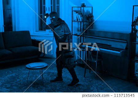 Lone figure in a room with a piano at night 113713545