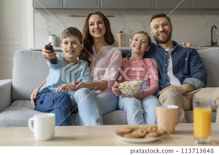 Family watching TV together, smiling joyfully at home Family watching TV together, smiling joyfully at home 113713648