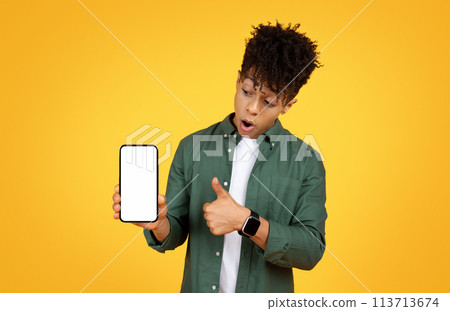Surprised young man holding smartphone 113713674