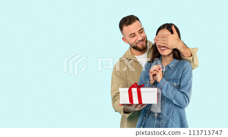 Man surprises woman with a gift on blue background 113713747