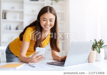 Woman texting while working on a project 113713808