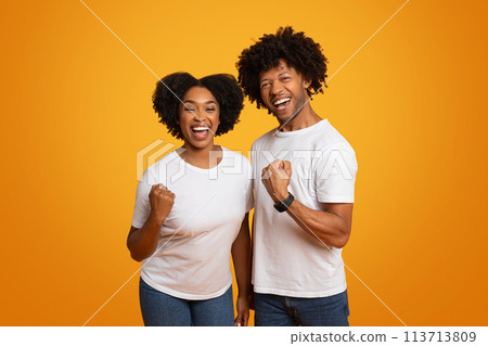 Emotional millennial african american couple celebrating success on yellow 113713809