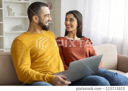 Happy couple using a laptop together at home 113713815