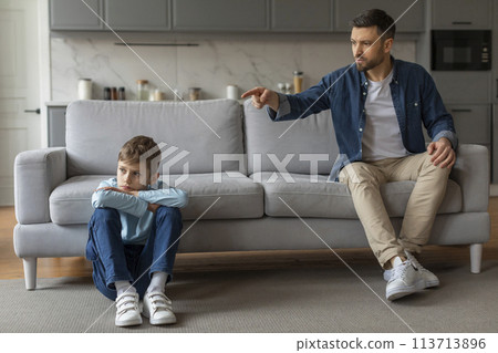 Man scolding a young boy sitting on floor Man scolding a young boy sitting on floor 113713896
