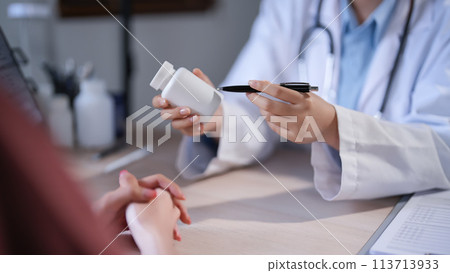 Asian psychologist women pointing on pills bottle to explaining medicine and prescription to female patient while giving counseling about medical and mental health therapy to female patient in clinic 113713933
