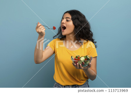 Woman eating salad on blue Woman eating salad on blue 113713969