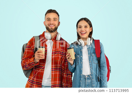 couple students posing with backpacks and takeaway coffee, blue background 113713995