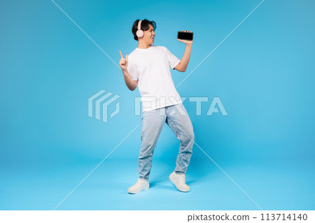 Guy dancing with smartphone on blue background 113714140