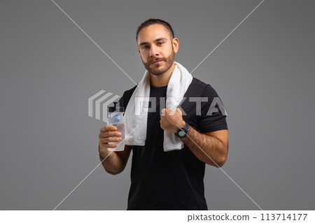 Focused athlete holding bottle and towel on grey background 113714177