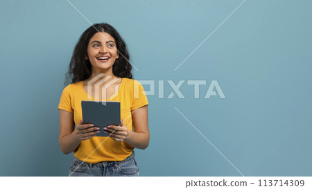 Joyful woman holding tablet on blue Joyful woman holding tablet on blue 113714309