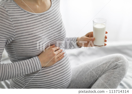 Pregnant woman holding a glass of milk 113714314