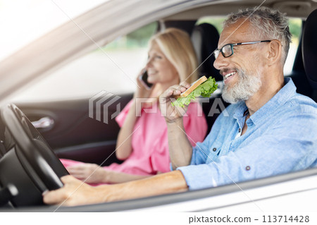 Elderly couple enjoying a salad sandwich in their car 113714428