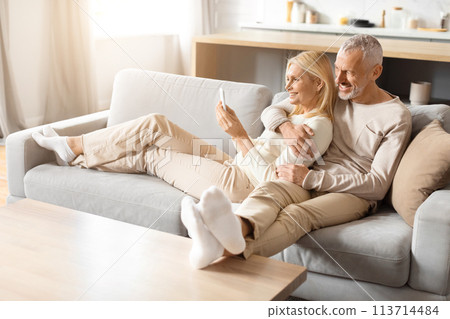 Couple relaxing on a minimalist couch in a bright room 113714484