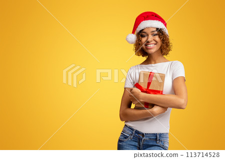 Woman with gift wearing Santa hat on yellow Woman with gift wearing Santa hat on yellow 113714528