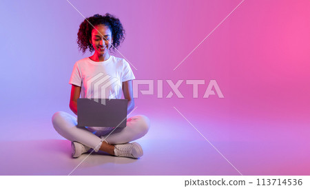 Woman with laptop sitting cross-legged Woman with laptop sitting cross-legged 113714536