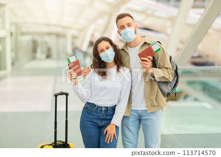 Happy Couple In Medical Masks Posing In Airport With Passports And Tickets Happy Couple In Medical Masks Posing In Airport With Passports And Tickets 113714570