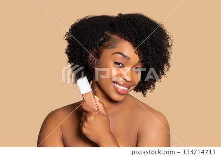 Gleaming black woman with foundation, perfecting makeup Gleaming black woman with foundation, perfecting makeup 113714711