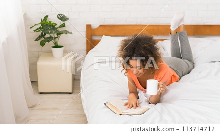 African-american girl reading book and drinking coffee 113714712