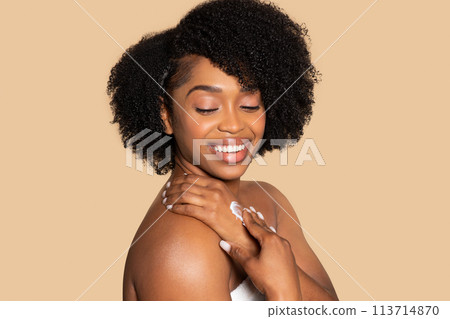 Happy black woman moisturizing hands, skincare routine joy Happy black woman moisturizing hands, skincare routine joy 113714870