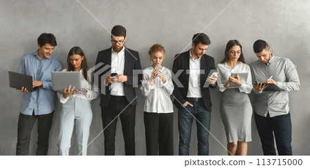 Business professionals using digital devices over grey wall 113715000