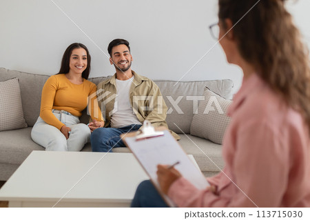 Smiling couple listens to therapist in session 113715030