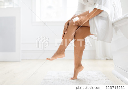 Woman moisturizing her leg in bright room Woman moisturizing her leg in bright room 113715231