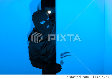 Thief peeking through the door at night Thief peeking through the door at night 113715237