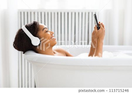 Woman unwinding in a tub with a smartphone Woman unwinding in a tub with a smartphone 113715246