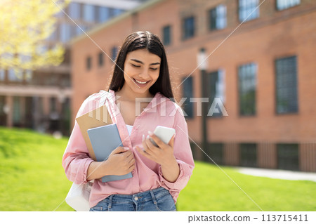Smiling student with phone and notebook outdoors 113715411