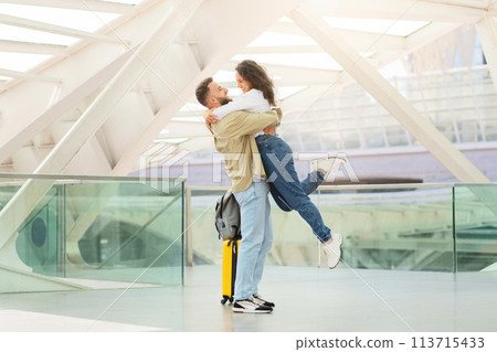 Loving couple embracing in airport terminal, man lifting woman off the ground Loving couple embracing in airport terminal, man lifting woman off the ground 113715433