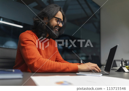 Joyful man typing on a laptop in the office 113715546