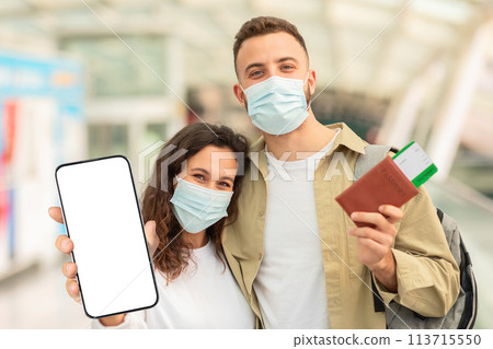 Couple Wearing Masks Holding Passports And Blank Smartphone At Airport 113715550