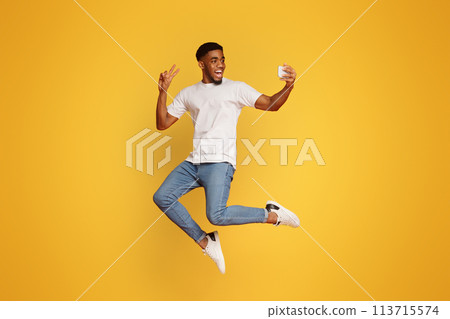 Happy man jumping and taking selfie on smartphone 113715574