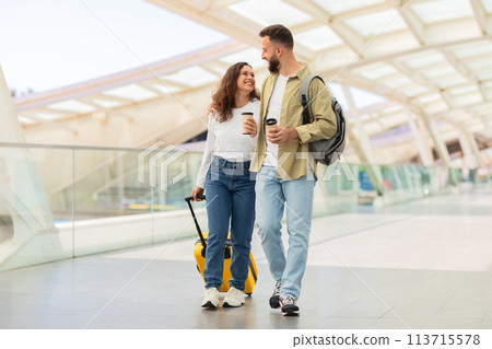 Man and Woman Walking Through Airport With Luggage And Takeaway Coffee 113715578