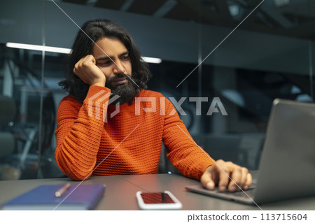 Man bored at work on laptop Man bored at work on laptop 113715604