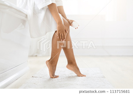Woman applying cream to her legs at home 113715681