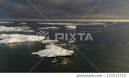 Antarctica aerial front view over islands covered with ice and snow. Icebergs in ocean water in Antarctic polar summer. Beautiful polar landscape. Drone forward flight. 113715715